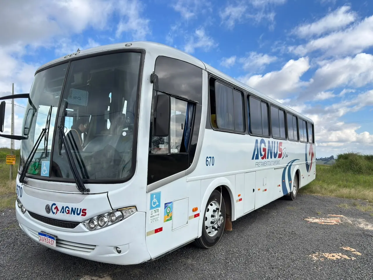 Ônibus da Agnus com a marca em azul e vermelho, visto de frente e pela lateral sob o céu azul.